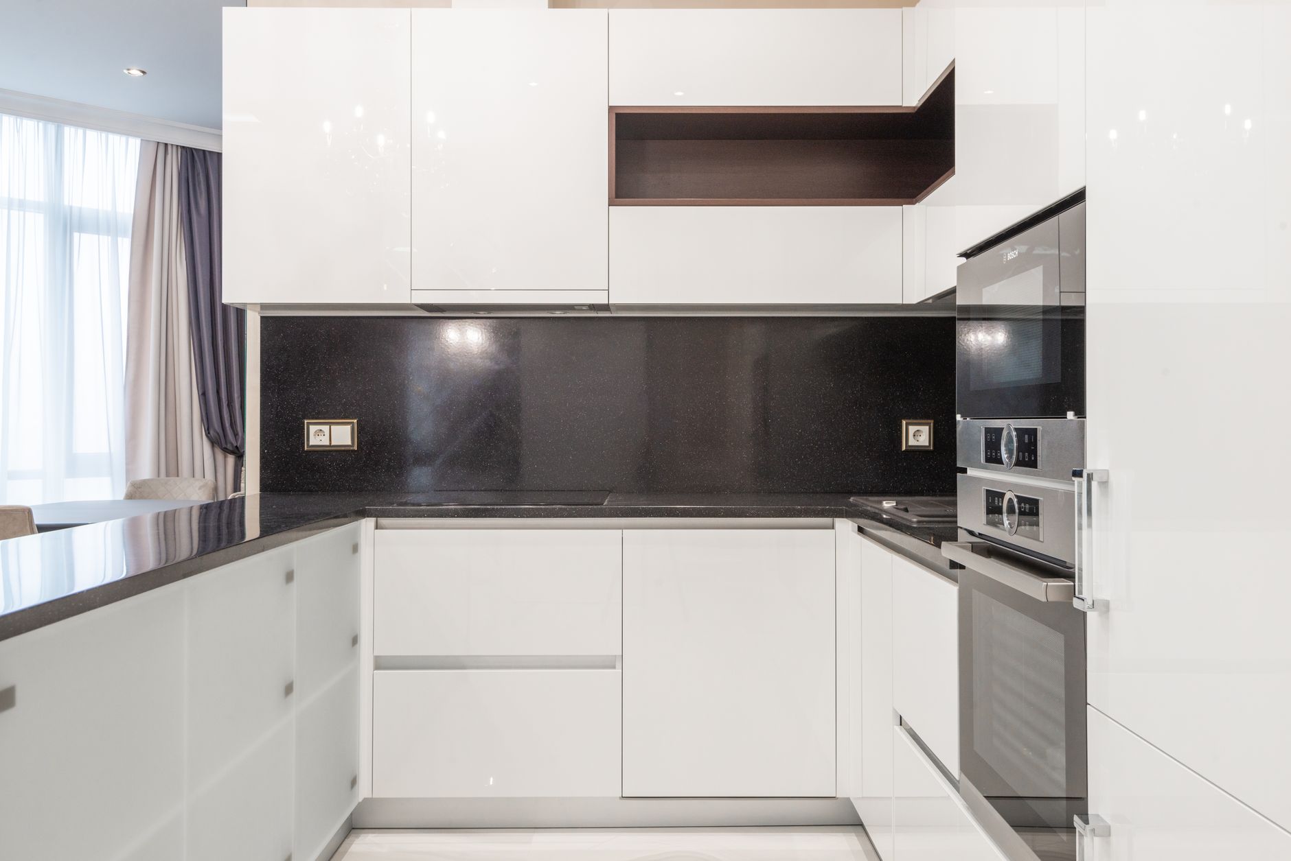 Sleek and clean modern kitchen with minimalist white cabinetry and black accents in Palm Springs, CA